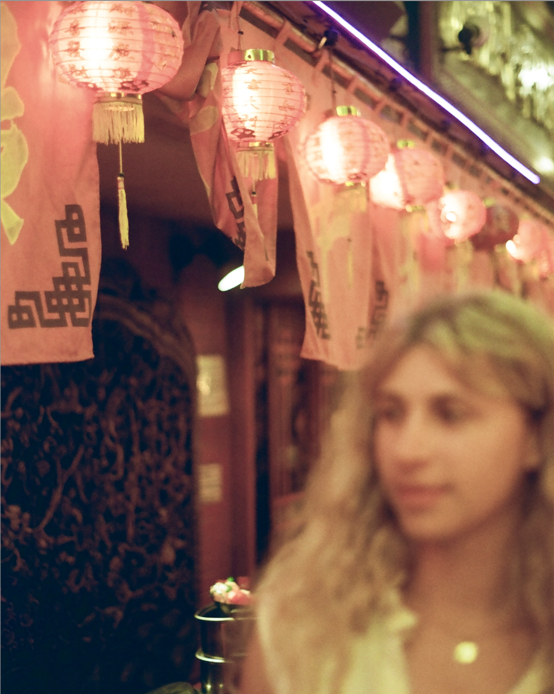 Row of pink Chinese lanterns and decorative banners with a blurred woman with blonde hair in the foreground.